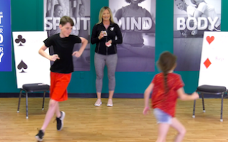 Y instructor leading exercise game for kids with cards