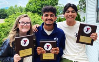 Three teens on deck outdoors, standing together for a photo holding their honor leader award plaque.