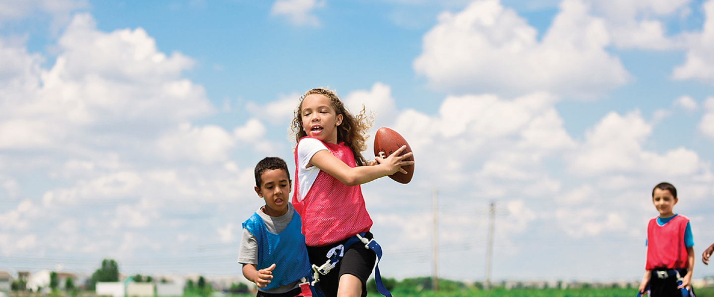 four kids playing flag football outside