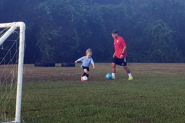 girl playing soccer with ymca coach