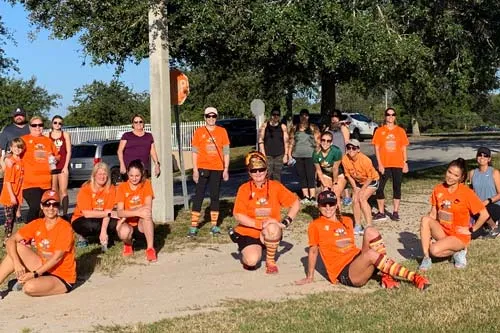 Group of runners wearing matching orange shirts outdoors 