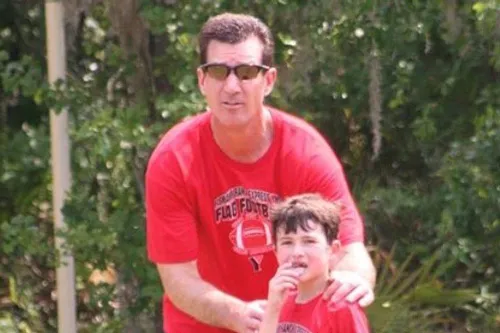 man wearing red shirt and sunglasses with and son outdoors