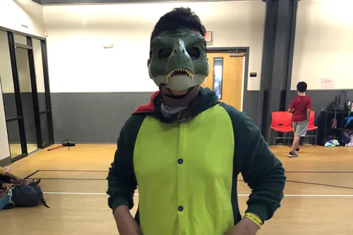 Kid wearing dinosaur mask inside YMCA gym