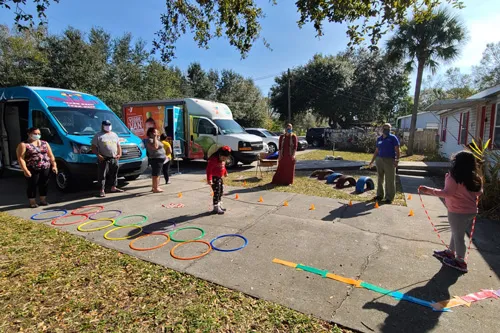 Kids and parents play games on pavement during BayCare mobile clinic and Veggie Van deliver checkups