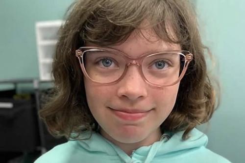 Headshot of young kid wearing green hoodie and eyeglasses