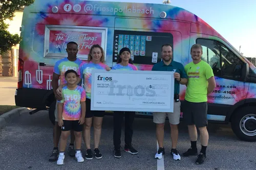 Birkhead family presenting check donation to Spurlino Y Executive Director and Program Director. The group of six standing with oversized check in front of the Frios Pops van.