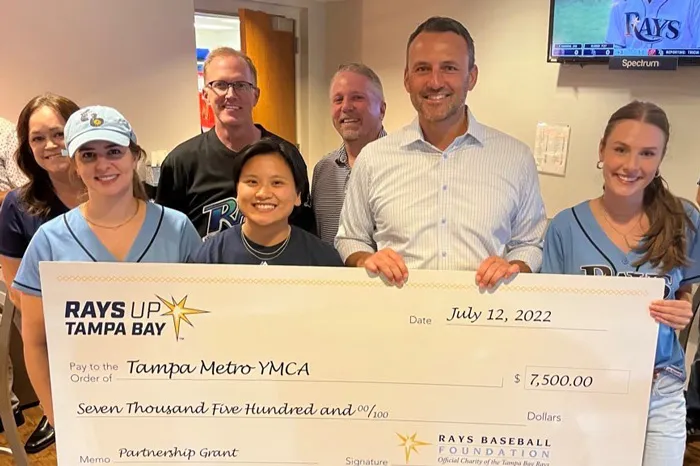 Seven Tampa YMCA staff members at check presentation at the Rays game.