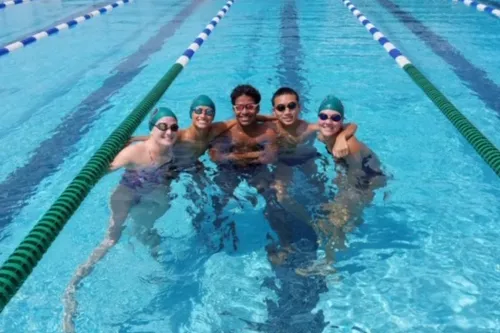 Five Tampa Y swim team members in a swim lane, smiling, posing for a photo.