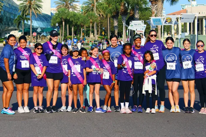 YMCA Camp Cristina Girls on the Run group photo and end of race May 2023. Group is wearing purple shirts in the bright sun – Dali Museum in the background.