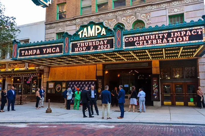 Group of people standing outside the Tampa Theater at dusk.