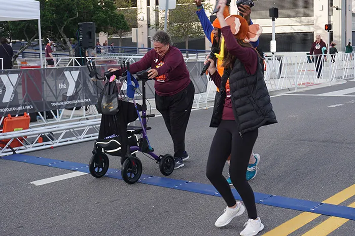2 women cheering on a Turkey Gobble participant with walker.