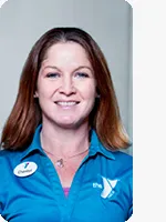 headshot of female personal trainer wearing blue YMCA polo gray background