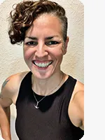 headshot of female personal trainer wearing black tank top beige background