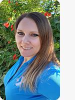 headshot of female personal trainer wearing blue YMCA polo plants in background