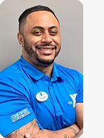 headshot of male personal trainer wearing blue YMCA polo gray background