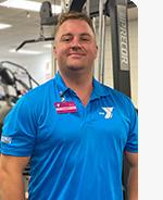 headshot of male personal trainer wearing light blue polo with Y logo in the gym