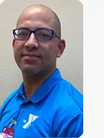 headshot of male personal trainer wearing blue YMCA polo in front of beige wall