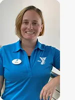 Staff member in light blue polo with white YMCA logo and short hair smiles for headshot