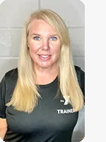 Female personal trainer wearing a black YMCA Trainer shirt in front of a gray wall.