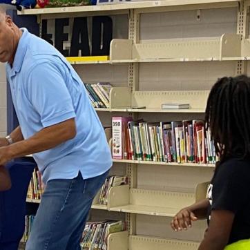 Former Buccaneers player Jerry Bell visits Sulphur Springs, demonstrating football moves with young student. 