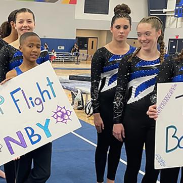 Top Flight Gymnastics Team hold signs of celebration