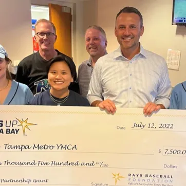 Seven Tampa YMCA staff members at check presentation at the Rays game. 