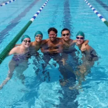 Five Tampa Y swim team members in a swim lane, smiling, posing for a photo.