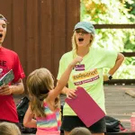 four camp counselors engaging campers at opening ceremony