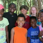 Seven kids pose together under the trees at Tampa Y's Camp Cristina.