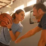 Daughter and father play Basketball at the YMCA.